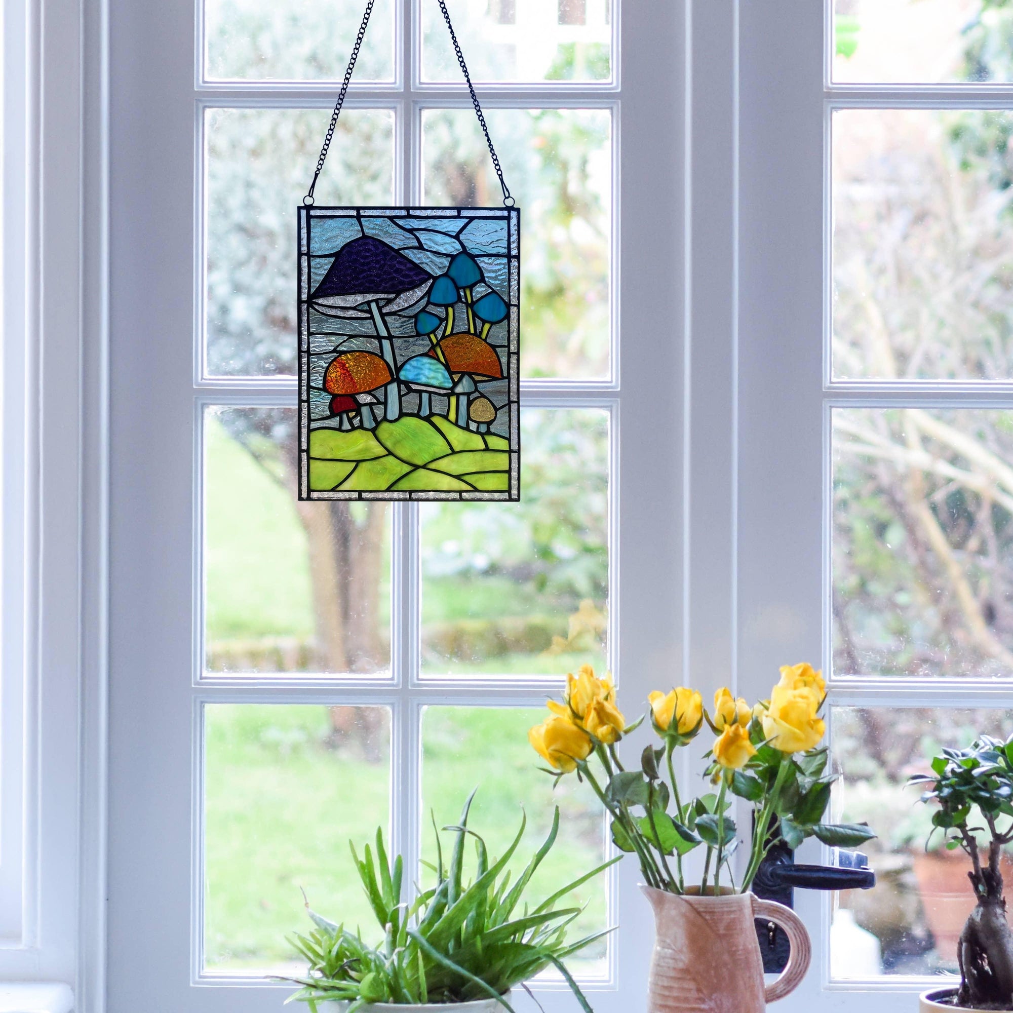 Mushroom Stained Glass Wall Hanging - Stained glass mushroom art piece displayed against a window with natural light creating vibrant colors and patterns.